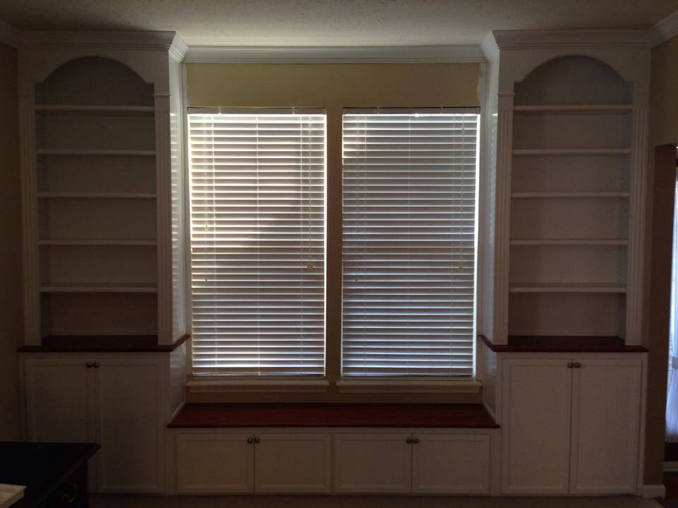 Window seat built-in with base cabinets, bookcases with arched headers, fluted column style face frames, crown molding and stained bench top and cabinet tops. 