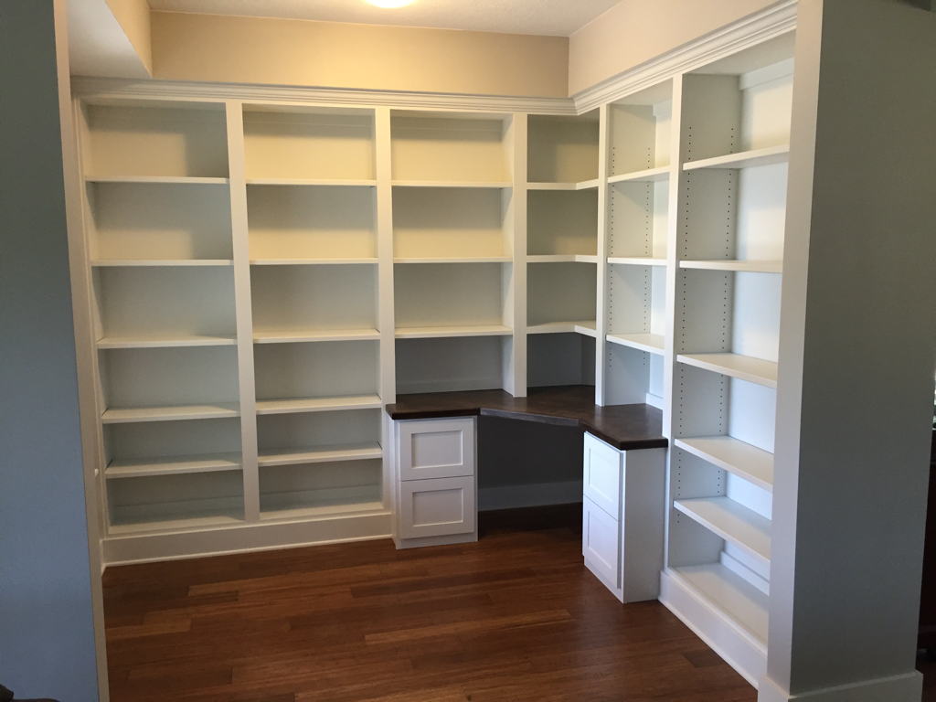 Custom office Built-in with corner desk with dark stained maple desktop,file cabinets, two walls of bookcases with adjustable shelving and crown molding. 